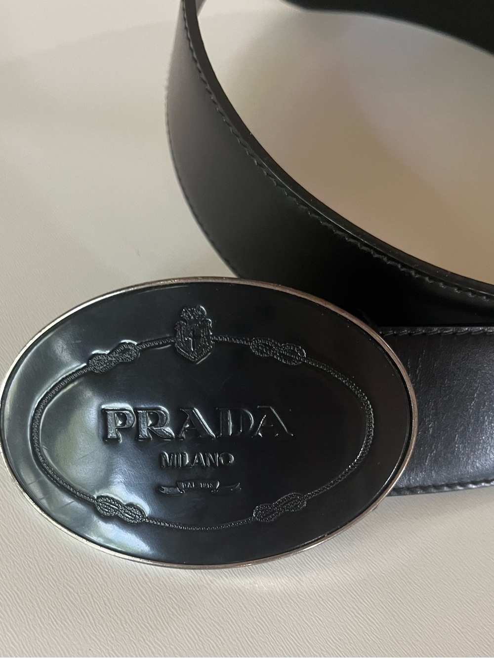 Prada Milano black leather belt, oval enamel buckle embossed w/ crest. Sz 34/86